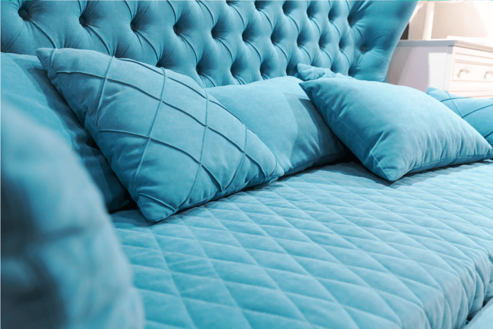 Person cleaning a gray fabric sofa cushion with a white cloth showing how to clean a couch at home
